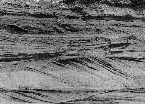 Black and white photograph. Horizontal bands of earth are independently striated in horizonal or diagonal layers.
